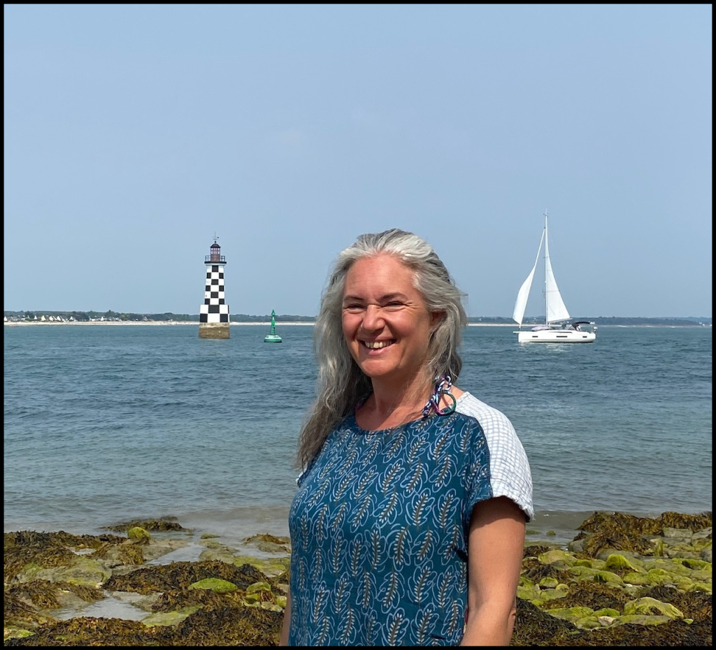 Photo de Christelle Humbertclaude devant le phare de la Perdrix à Loctudy et un voilier blanc sur l'eau